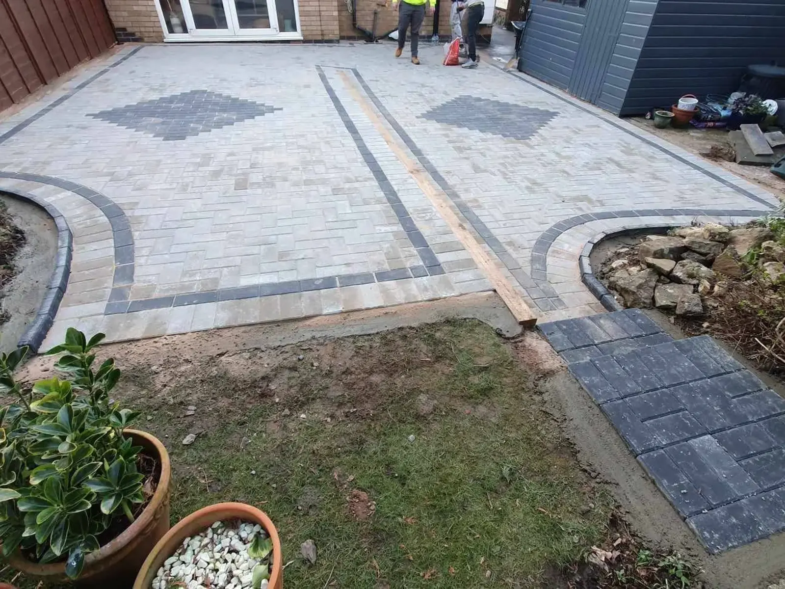 Grey driveway with charcoal bands and curved edging