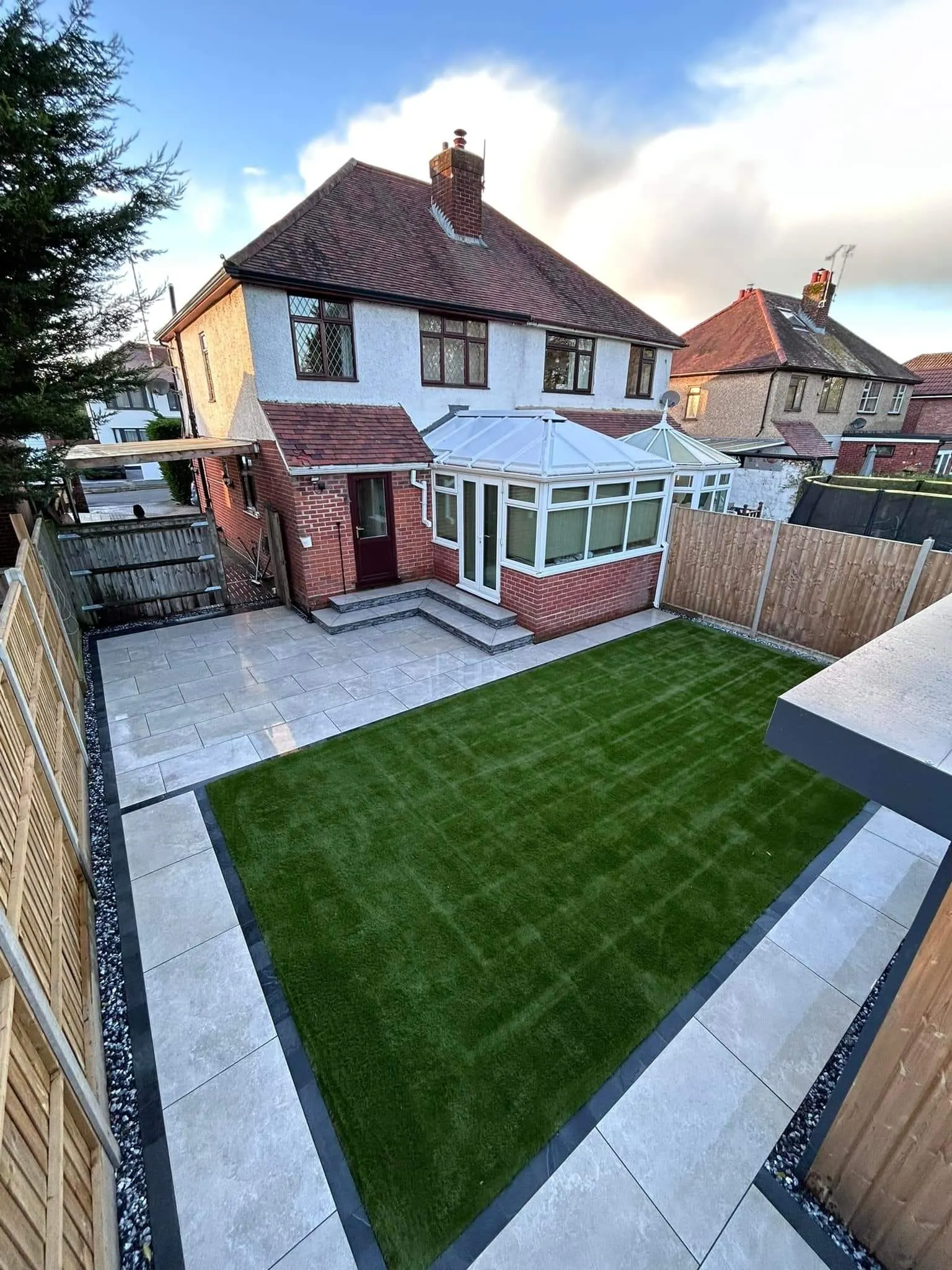 Artificial grass framed by porcelain paths behind a semi-detached house