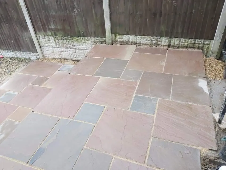 Autumn brown sandstone patio with a gravel edge in a fenced garden