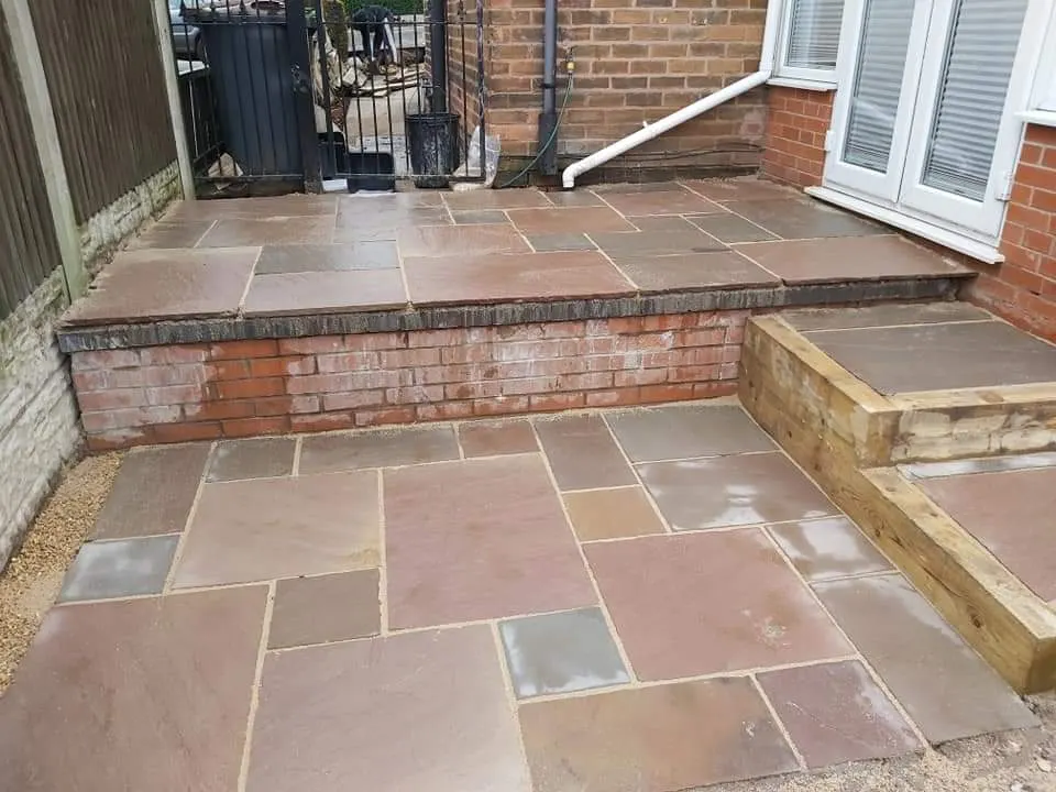 Two-level autumn brown sandstone patio with sleeper steps below French doors