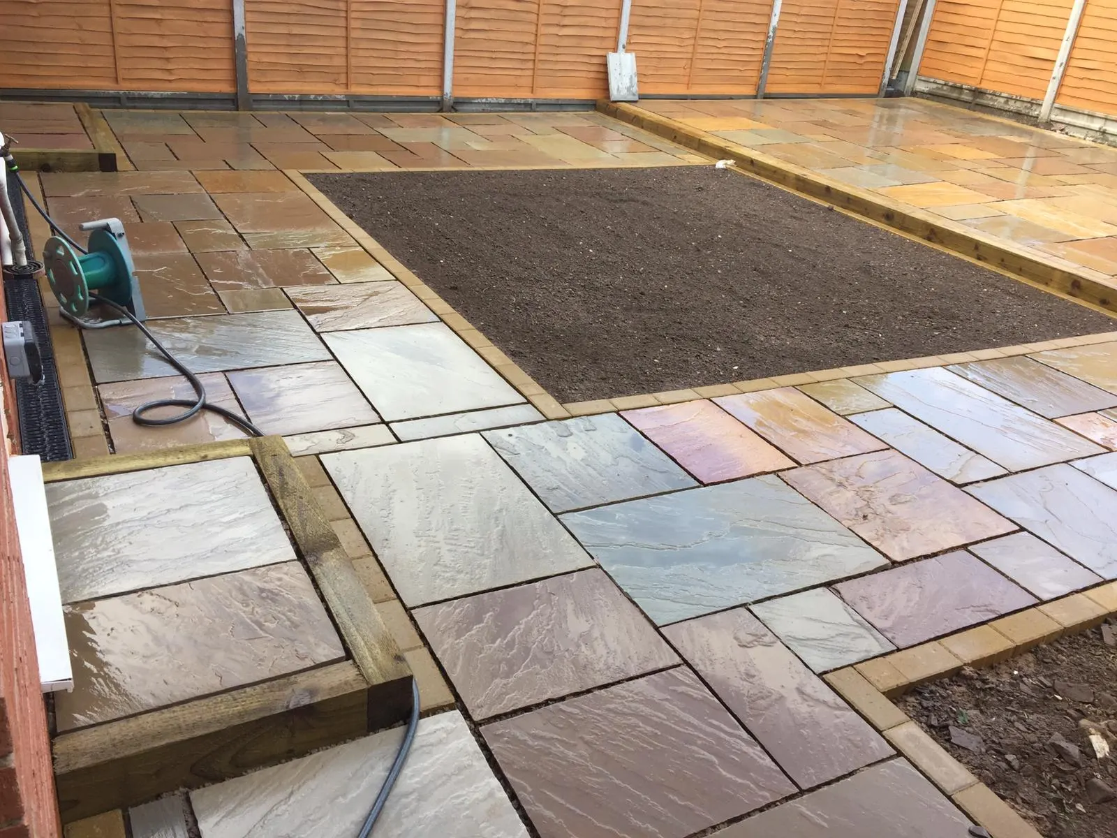 Sandstone patio round a planting bed edged with sleepers