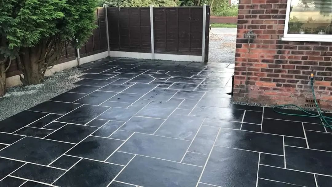 Black slate patio with a gravel border beside a brick house