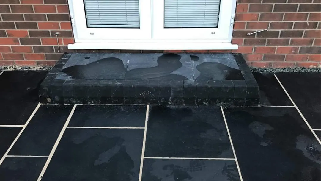 Black slate patio with a step under a window