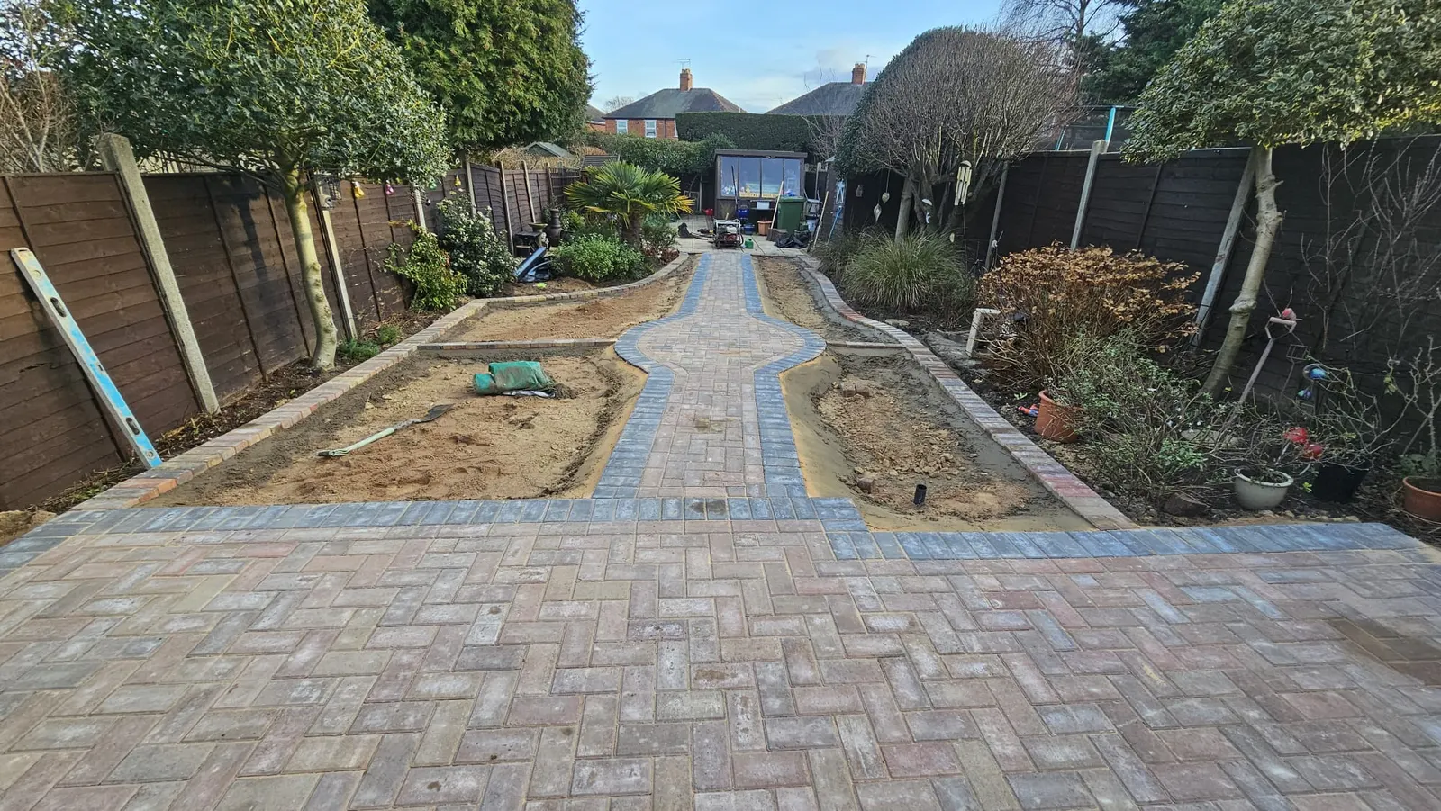 Block paving garden paths with charcoal borders between new planting beds
