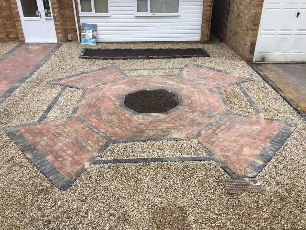 Red block paving hexagon feature set in a gravel drive