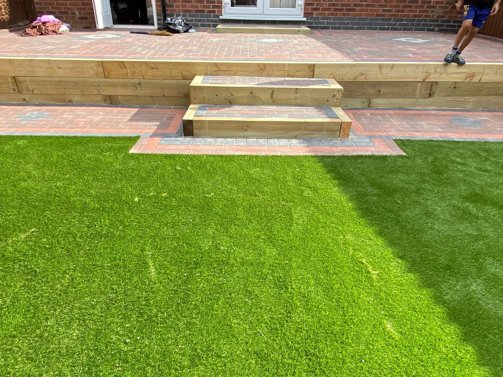 Block paving terrace with sleeper steps down to the lawn