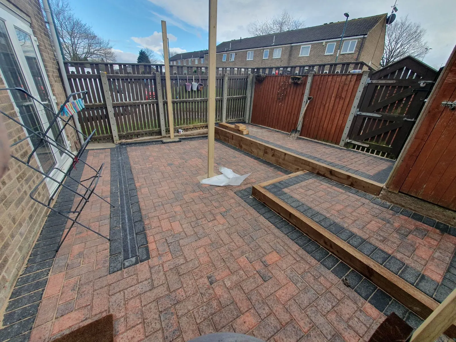 Brindle block paving back garden with charcoal bands and a sleeper raised bed