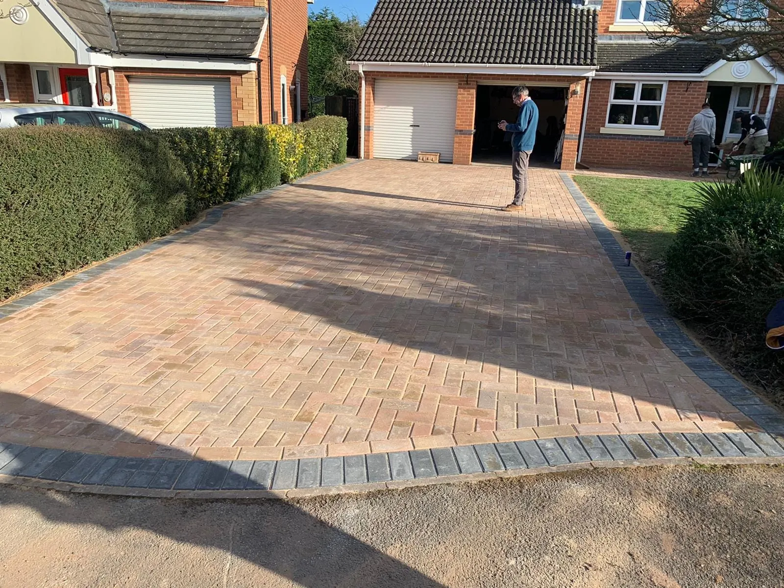 Brindle herringbone block paving driveway with a charcoal border up to a garage