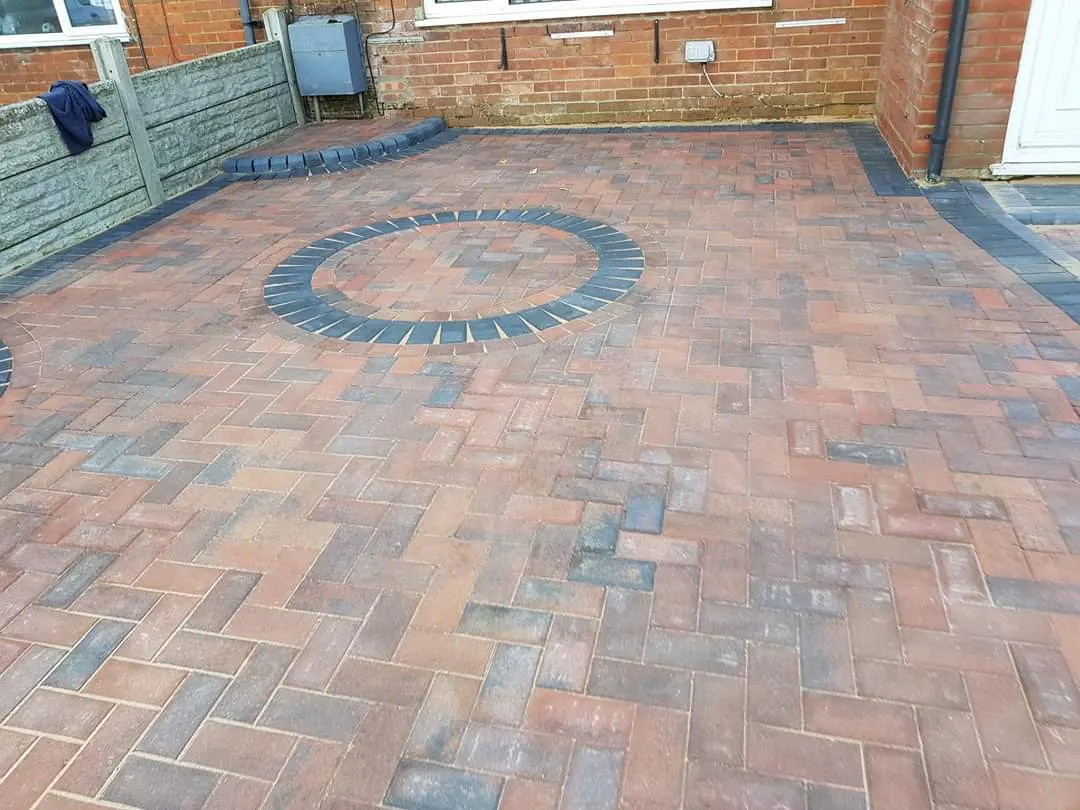 Brindle block paving driveway with a charcoal circle inset at a semi-detached house