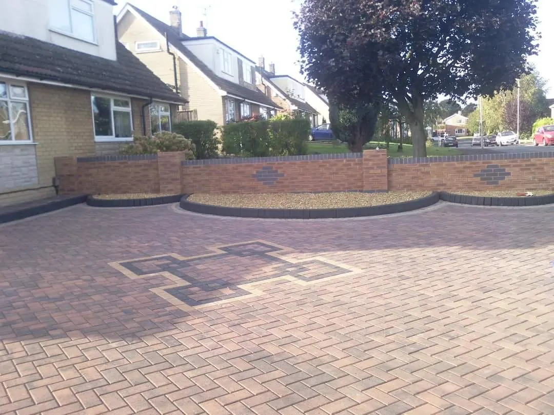 Brindle herringbone block paving driveway with a cross feature and a curved brick wall