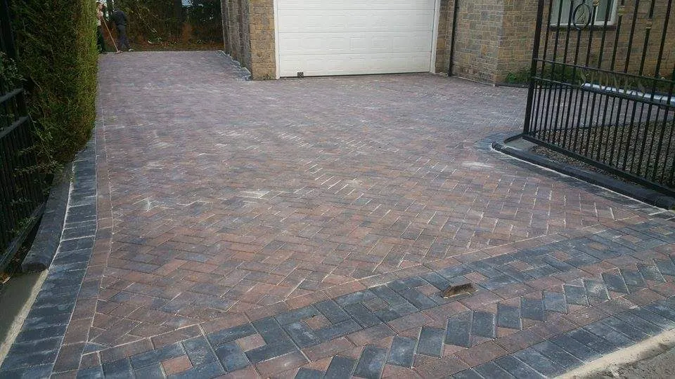 Brindle block paving driveway behind gates with a patterned border