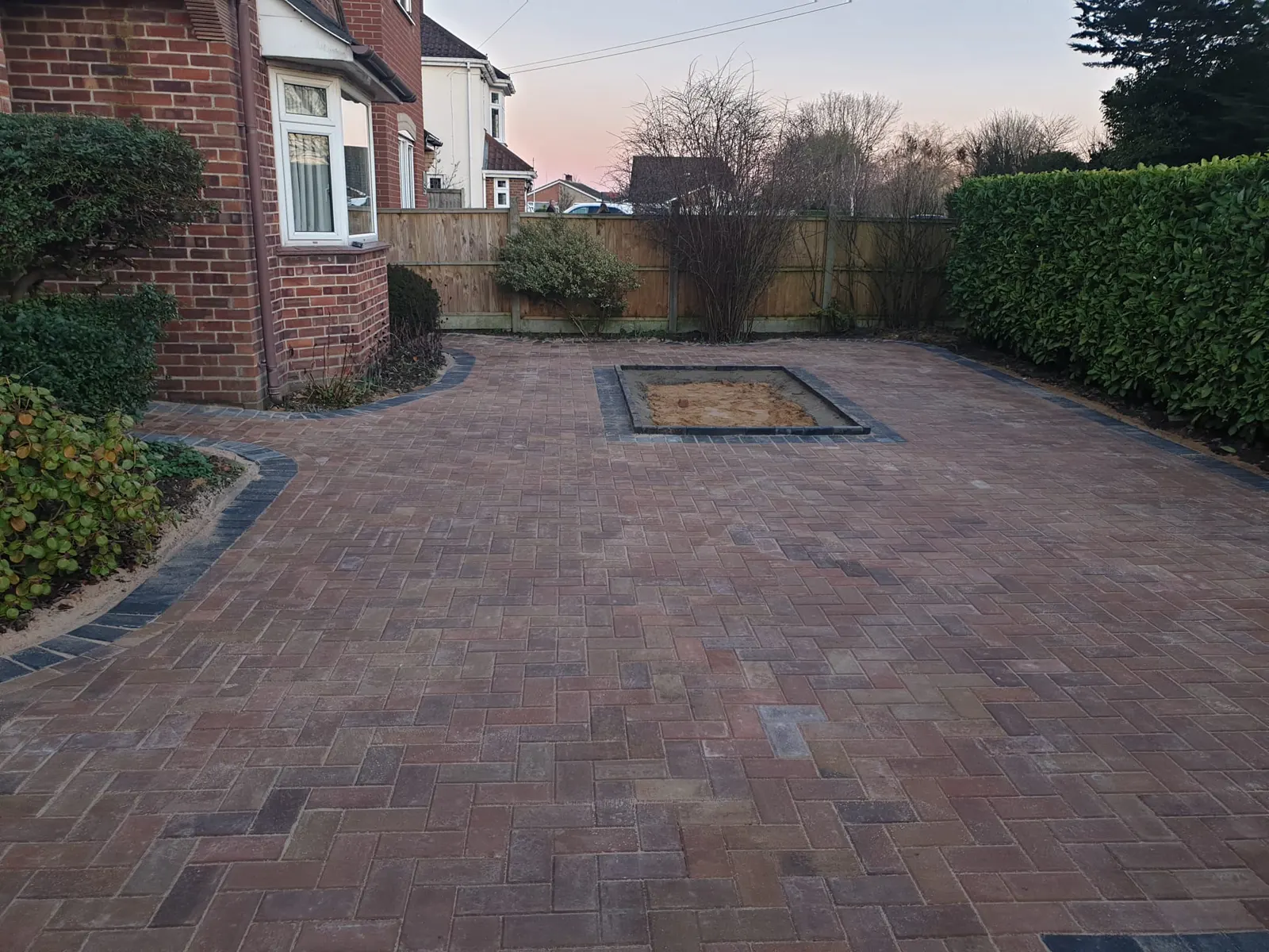 Brindle block paving driveway beside a hedge in the evening light