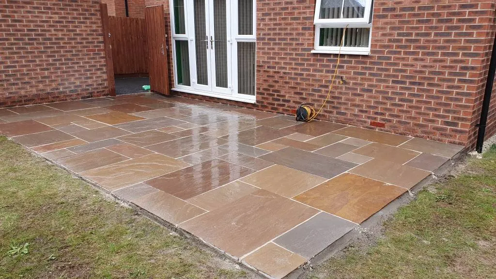 Buff Indian sandstone patio behind a new-build house