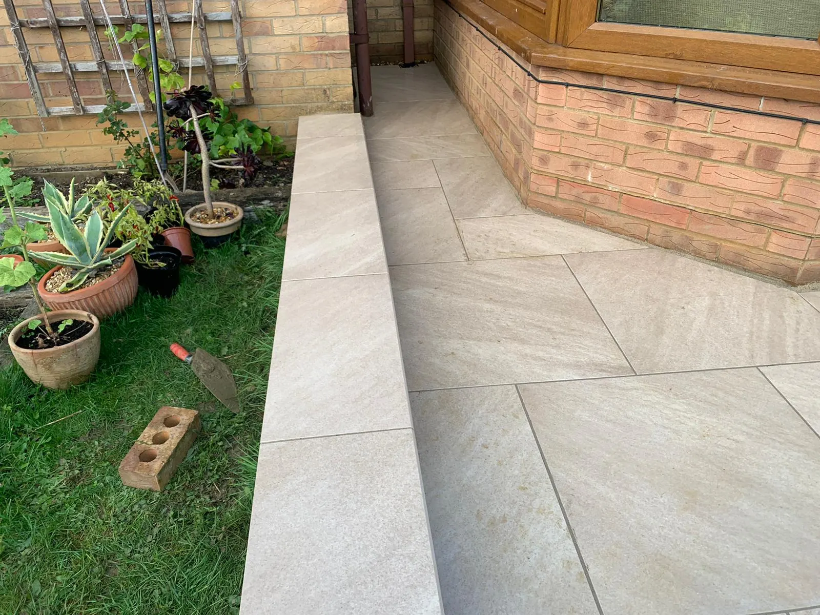 Buff porcelain path with a raised step beside a lawn