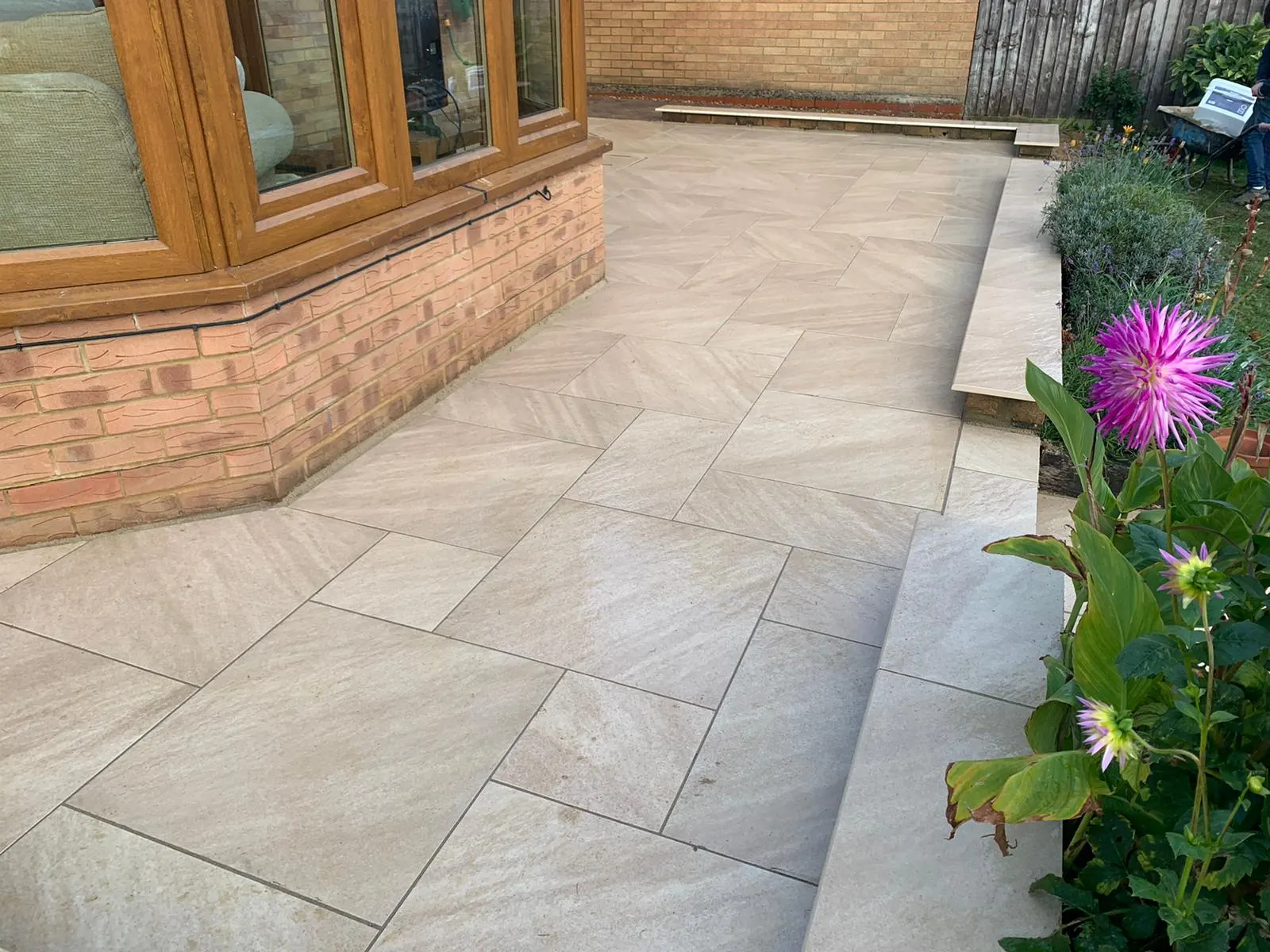 Buff porcelain patio by a bay window with flower beds