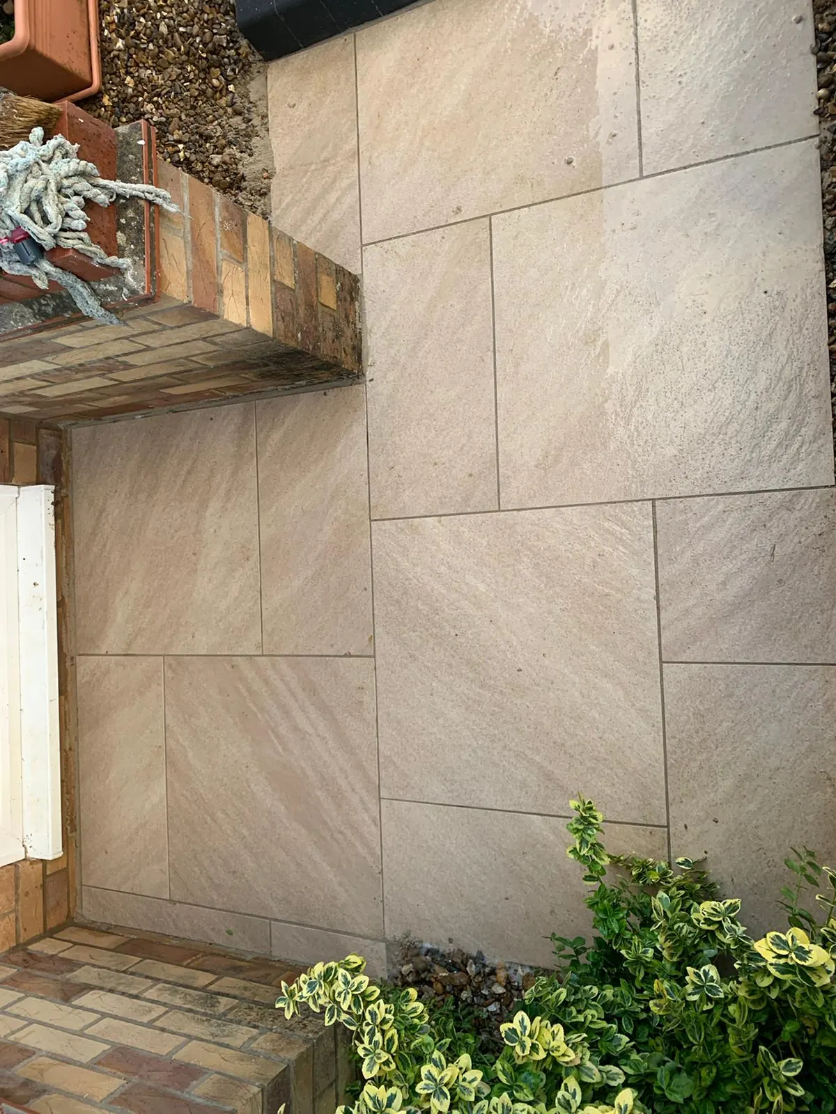 Buff porcelain patio beside a brick raised bed