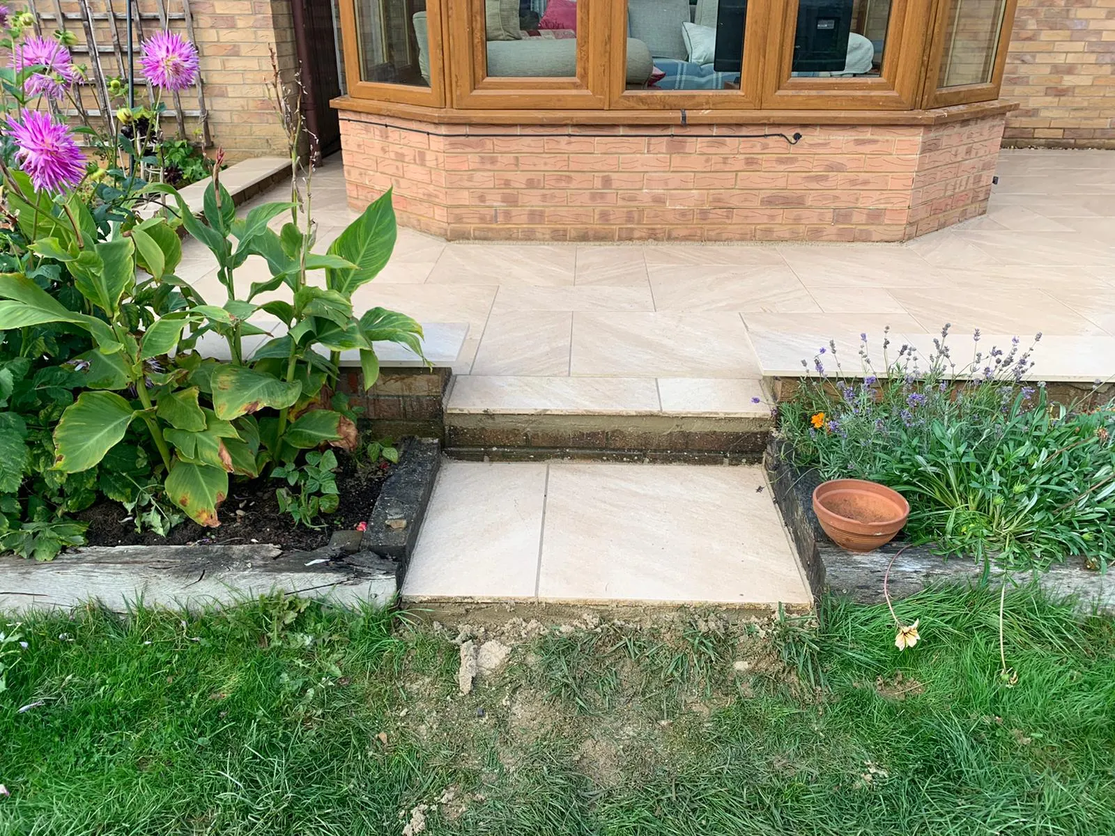 Buff porcelain patio with steps between flower beds