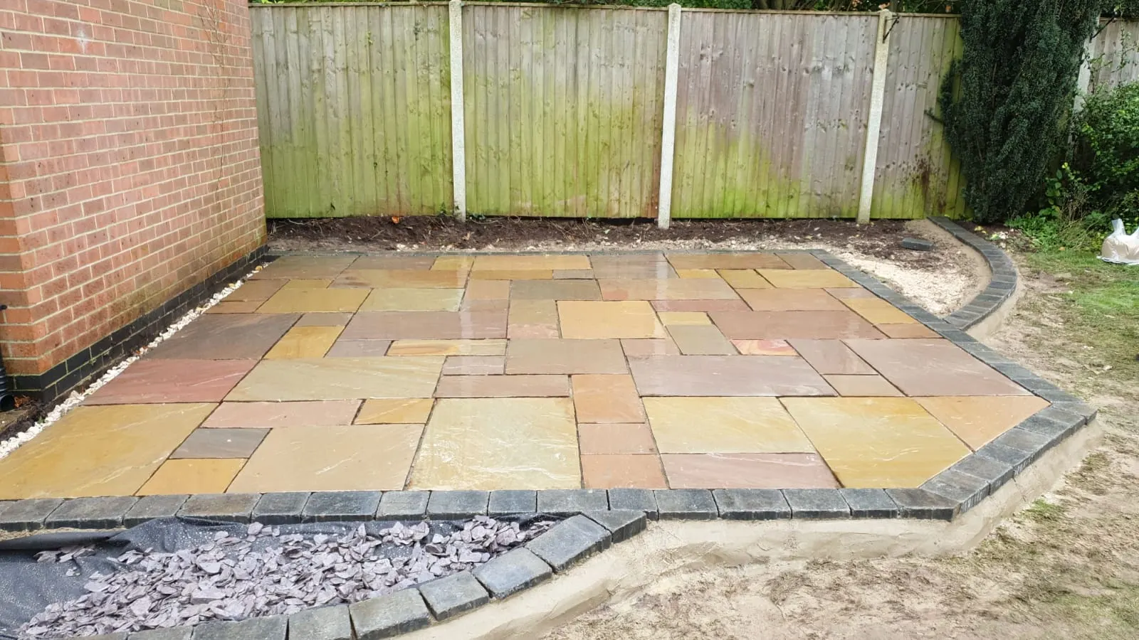 Buff sandstone patio with a charcoal border and slate chippings