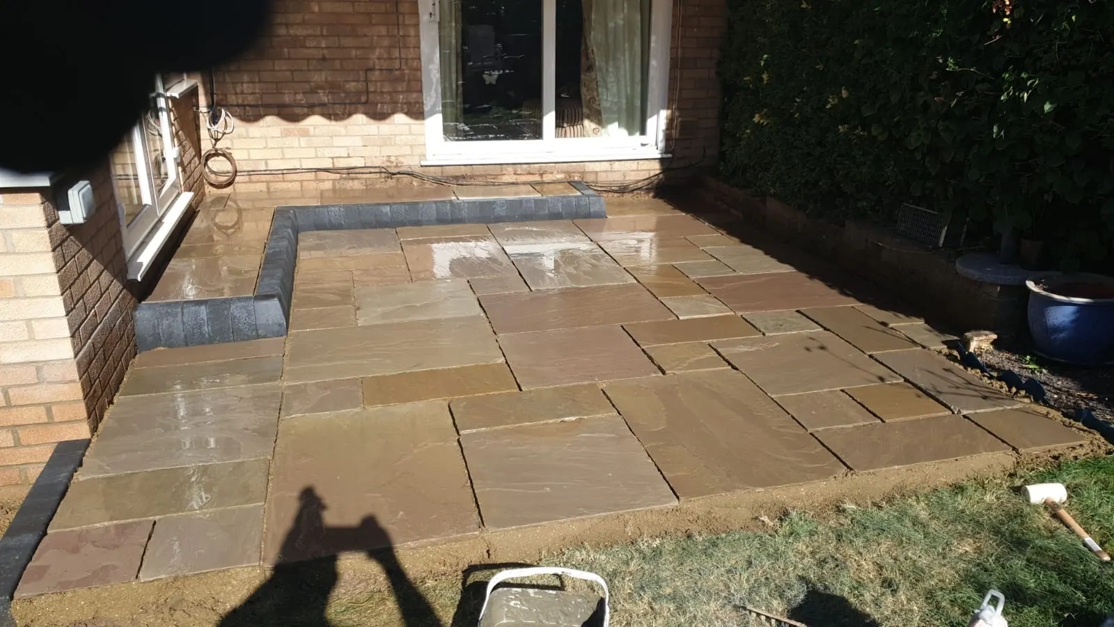 Buff sandstone patio with a charcoal kerb in the evening