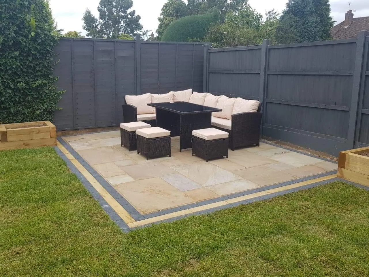 Buff sandstone patio with a charcoal border and garden furniture