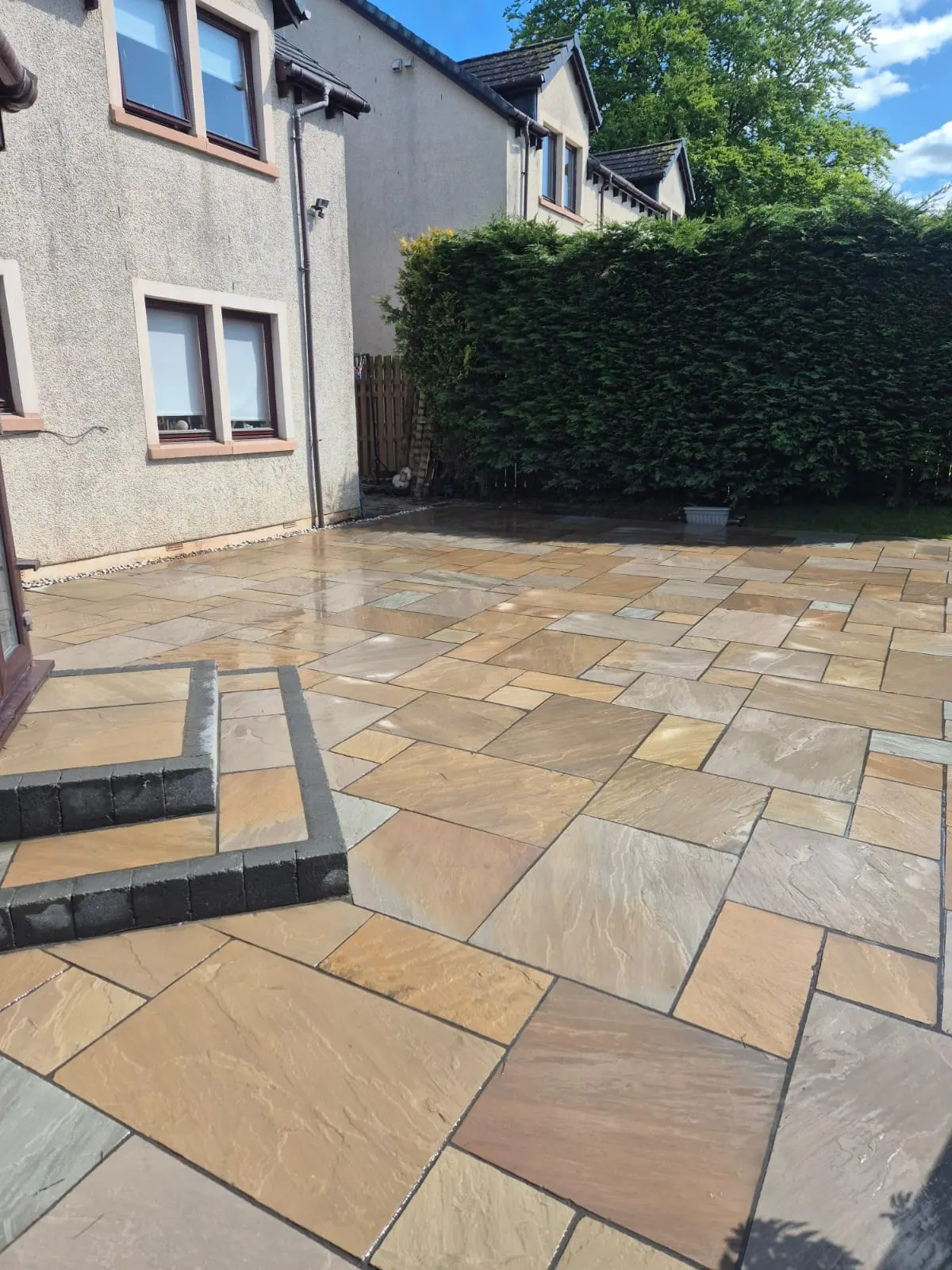 Buff sandstone patio with a raised step at a semi-detached house