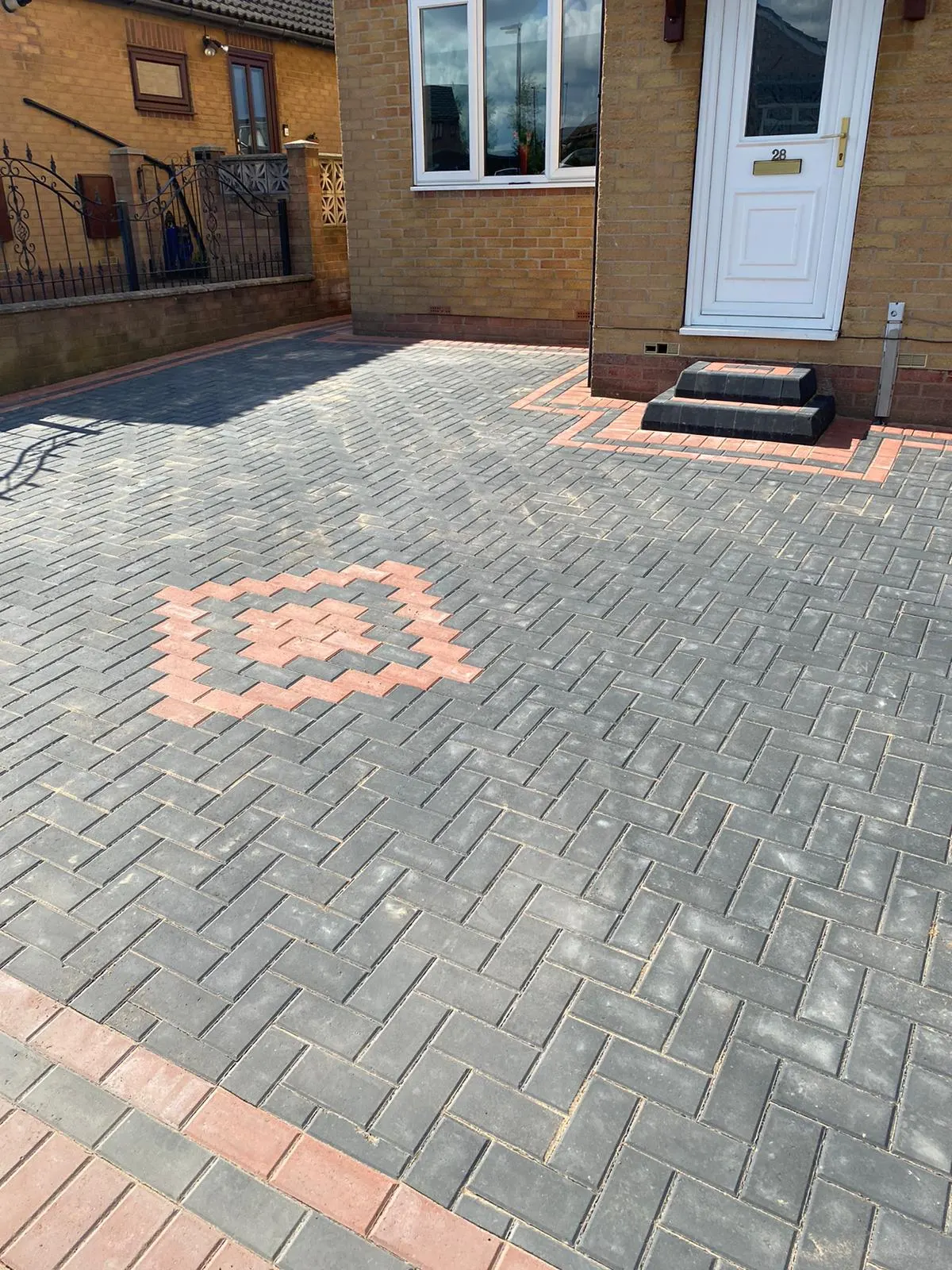 Charcoal herringbone block paving driveway with a red diamond feature