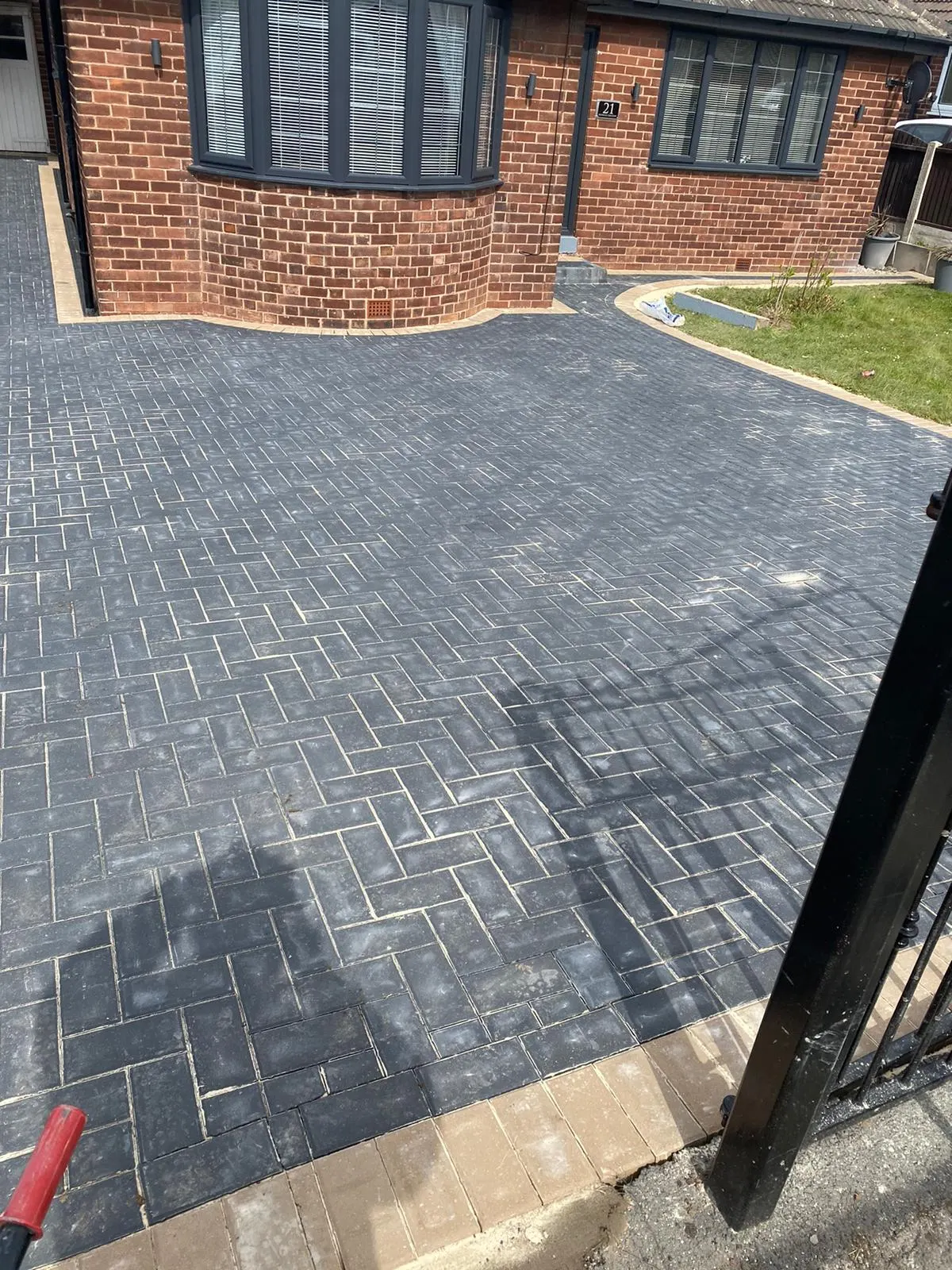 Charcoal herringbone block paving driveway by a bay window