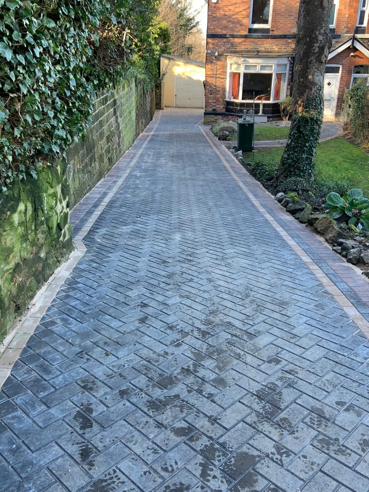 Charcoal block paving path in herringbone along a side garden
