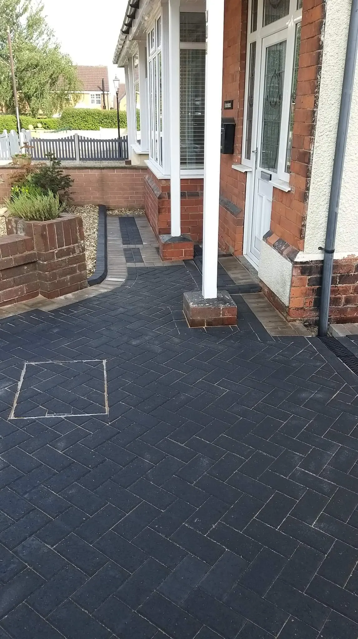 Charcoal block paving path by a porch with a recessed cover