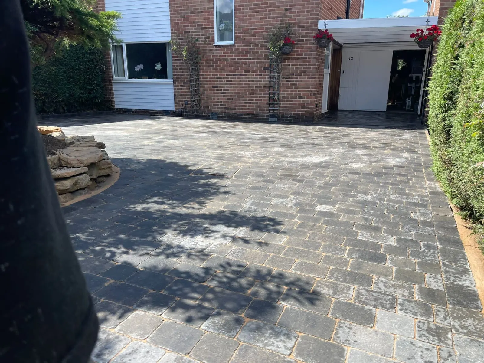 Charcoal cobble-effect block paving driveway with a stone rockery
