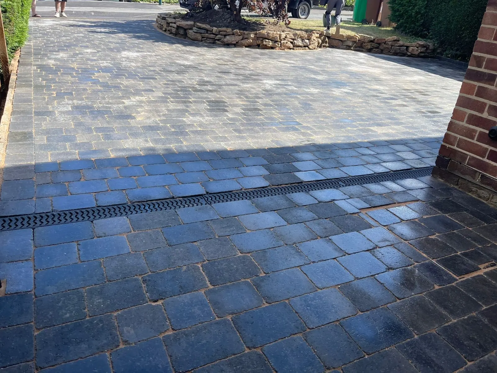 Charcoal cobble-effect block paving with a channel drain, wet after rain