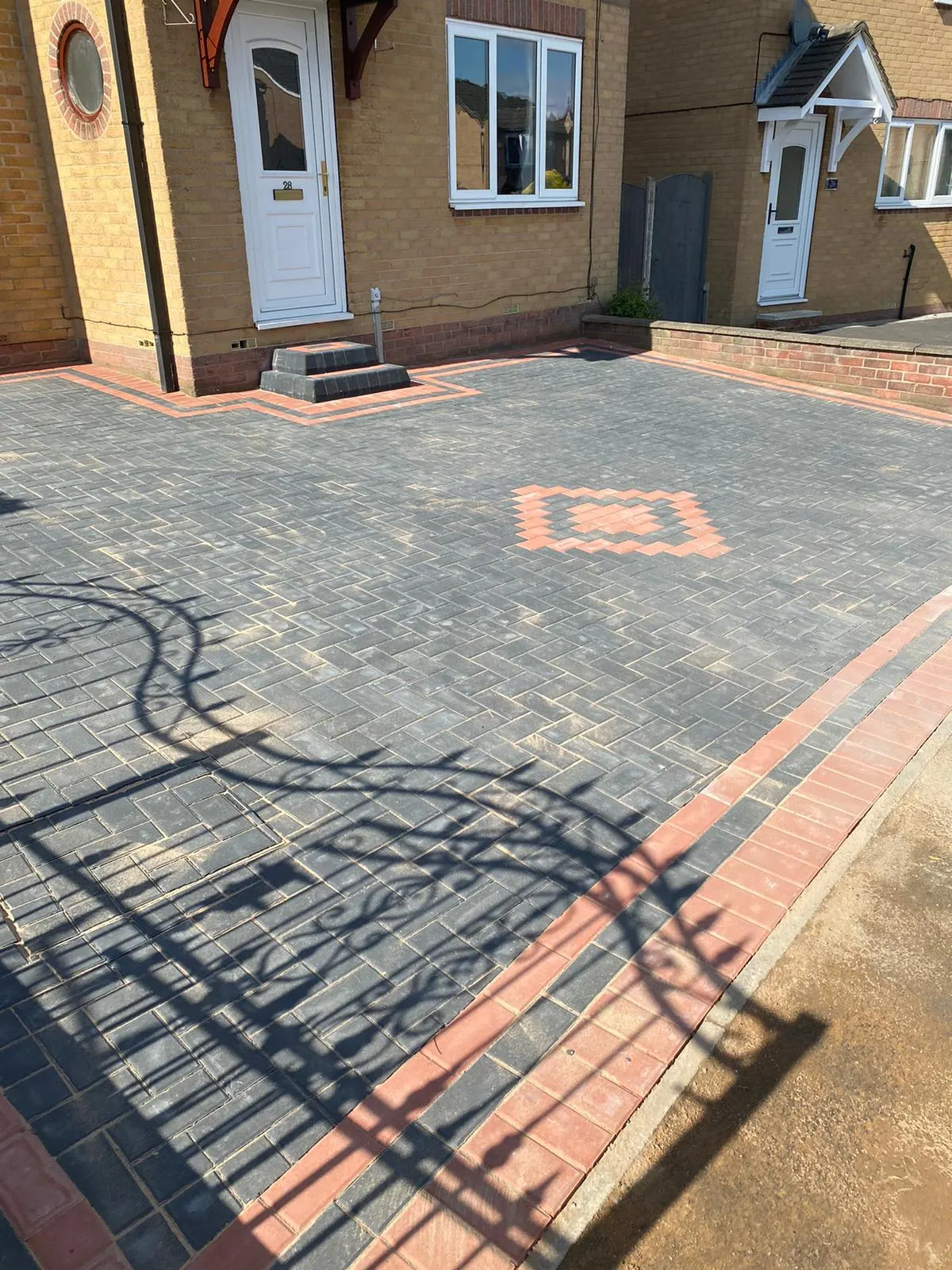 Charcoal herringbone block paving driveway with a red border and front steps