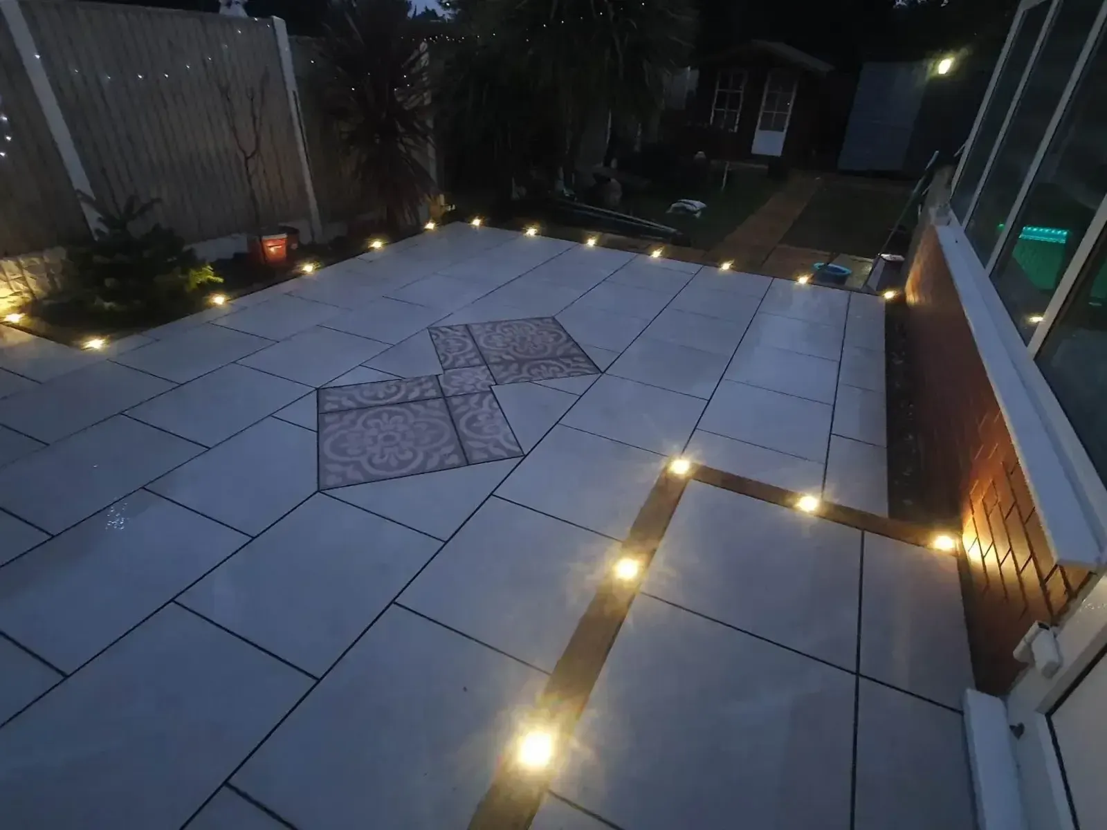 Charcoal porcelain patio with LED edge lights at dusk