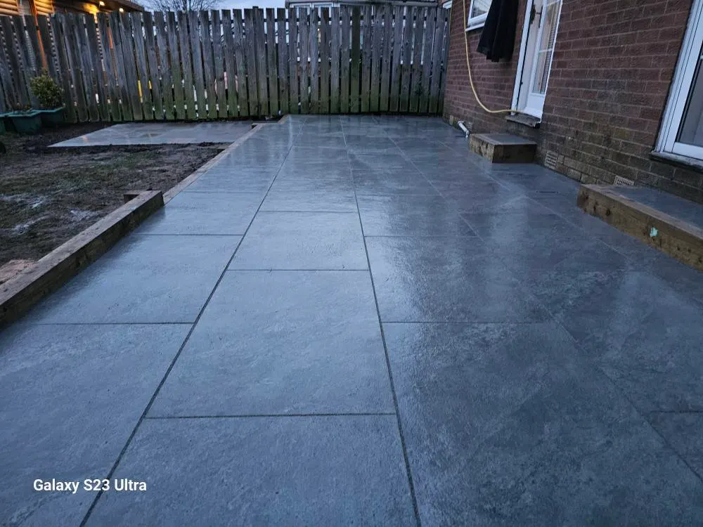 Charcoal porcelain patio with a sleeper edge in a rear garden