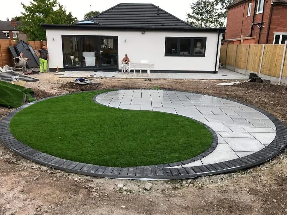 Circular lawn and curved porcelain patio with a charcoal edge