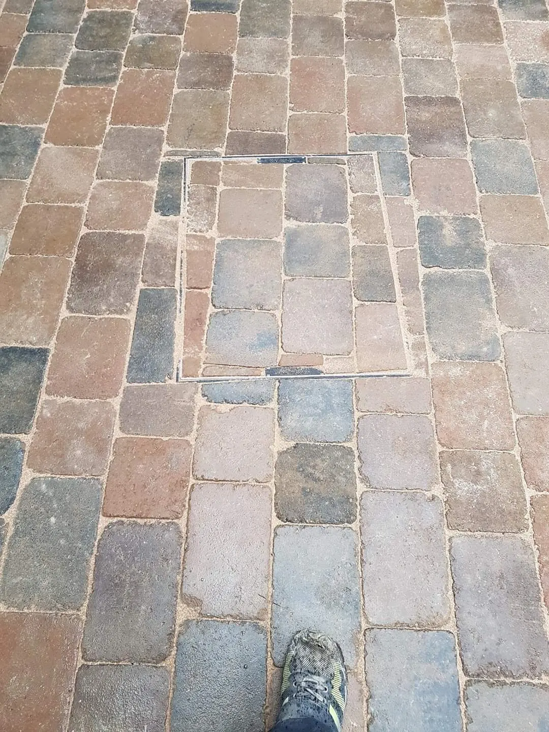 Cobble-effect block paving laid round a recessed manhole cover
