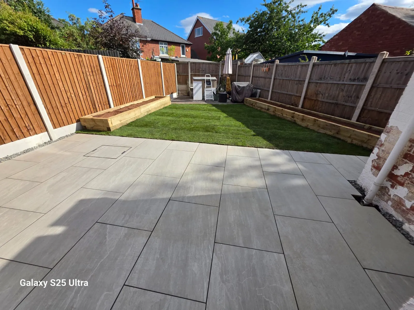 Cream porcelain patio with artificial grass and sleeper raised beds