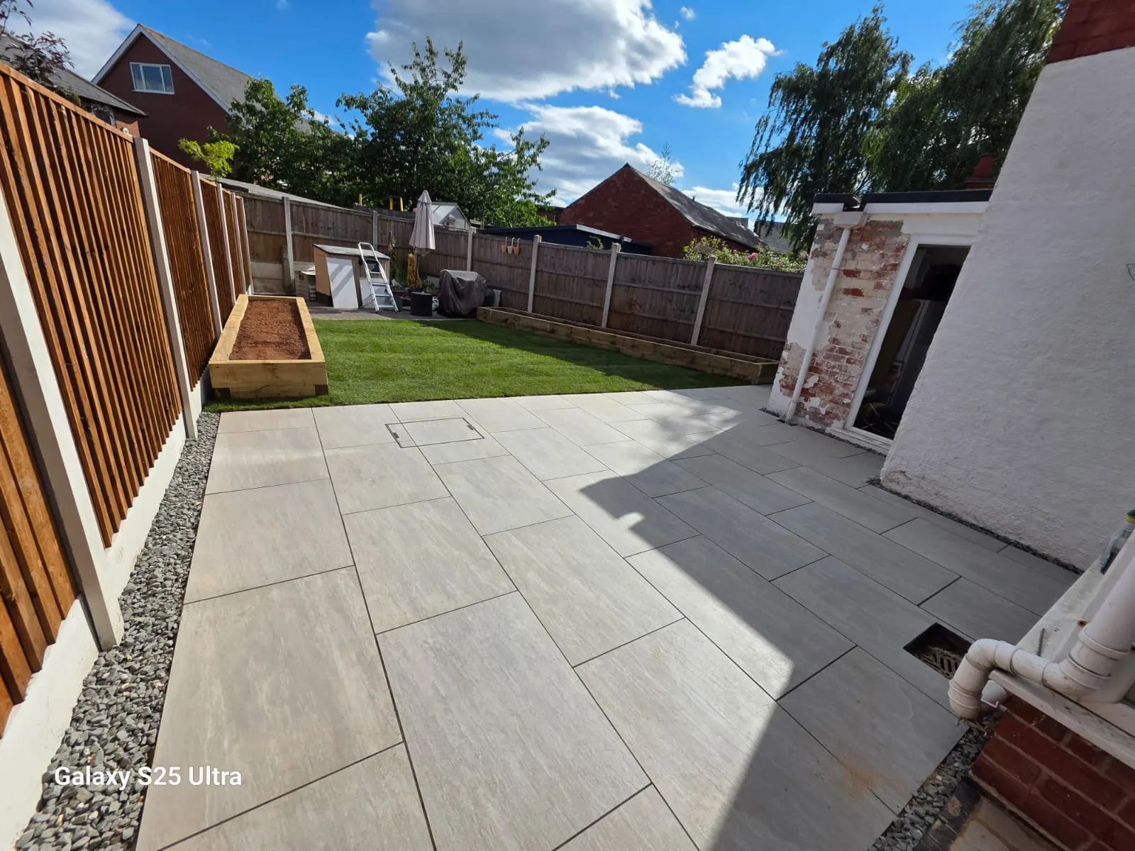 Cream porcelain patio with a gravel strip and a raised planter