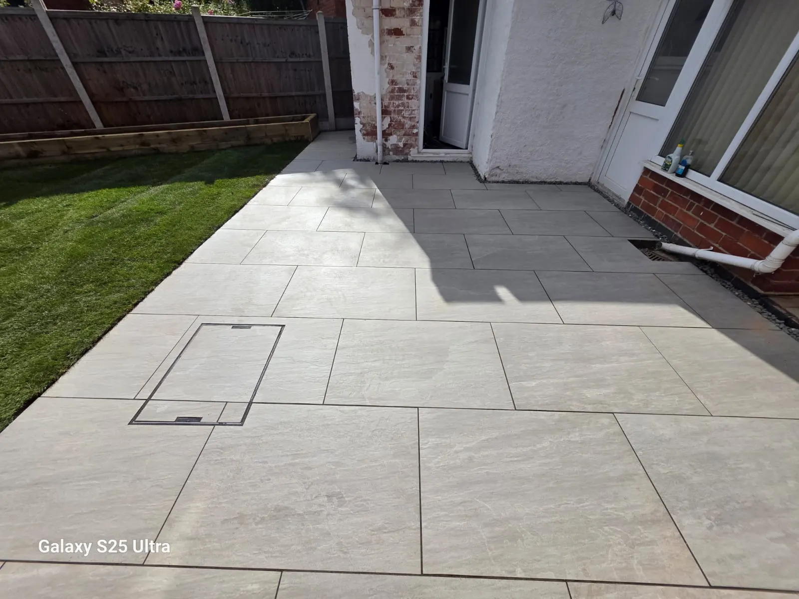 Cream porcelain patio with a recessed cover beside a lawn