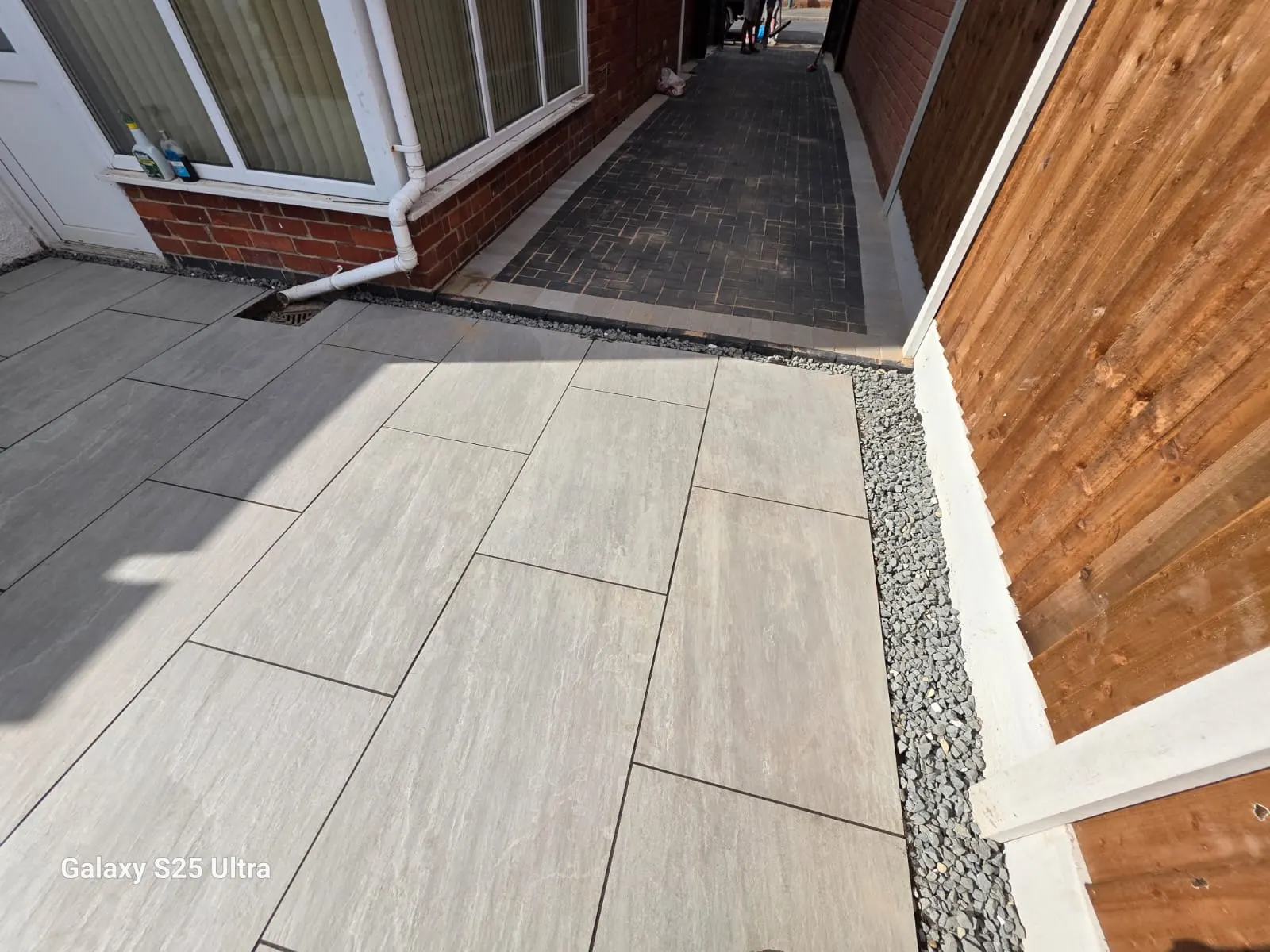 Cream porcelain side patio with a gravel strip along the fence