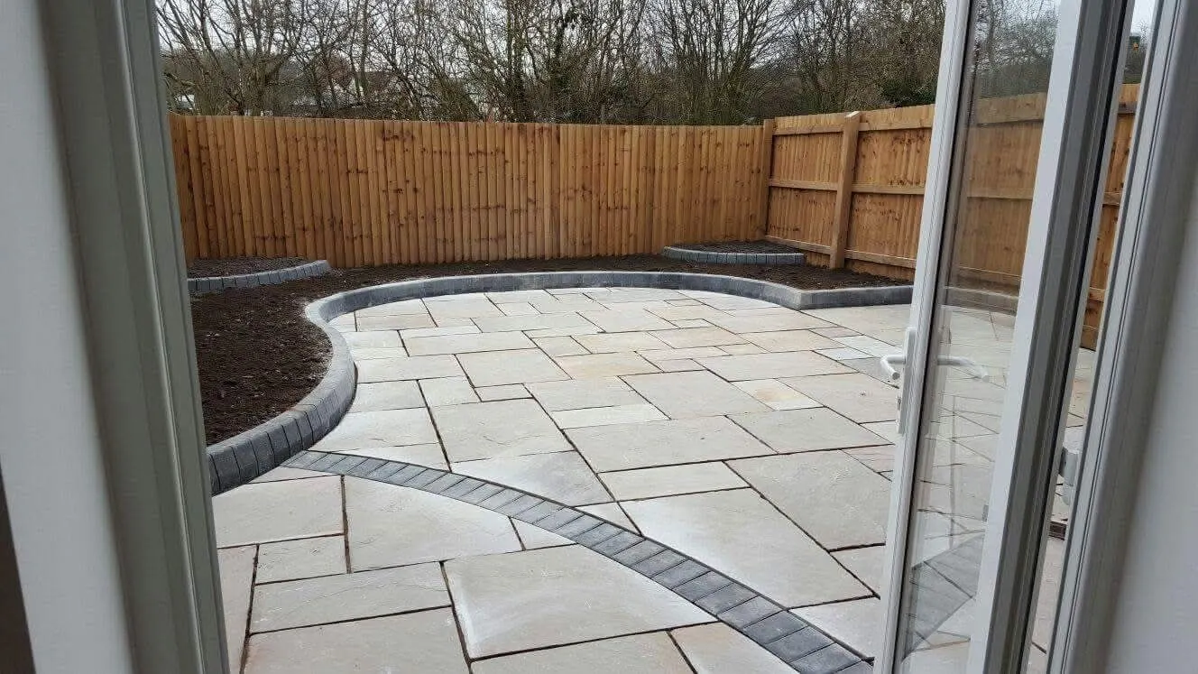 Curved Indian sandstone patio with a block paving edge, seen from the patio doors