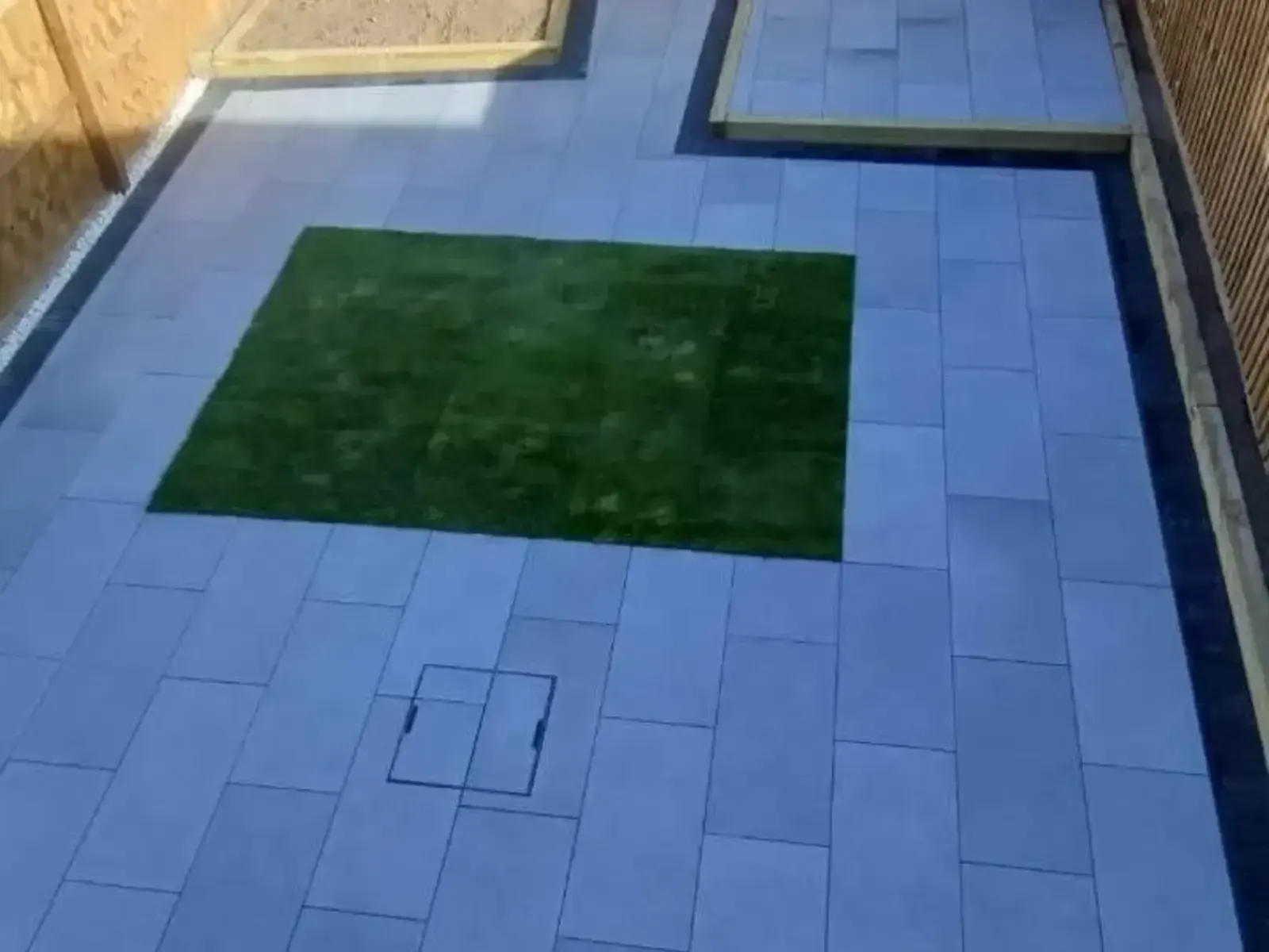 Dark porcelain patio with an inset square of artificial grass