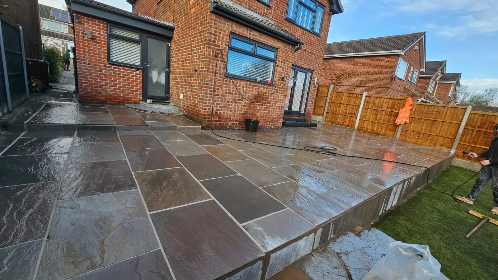 Dark sandstone patio at the back of a detached house