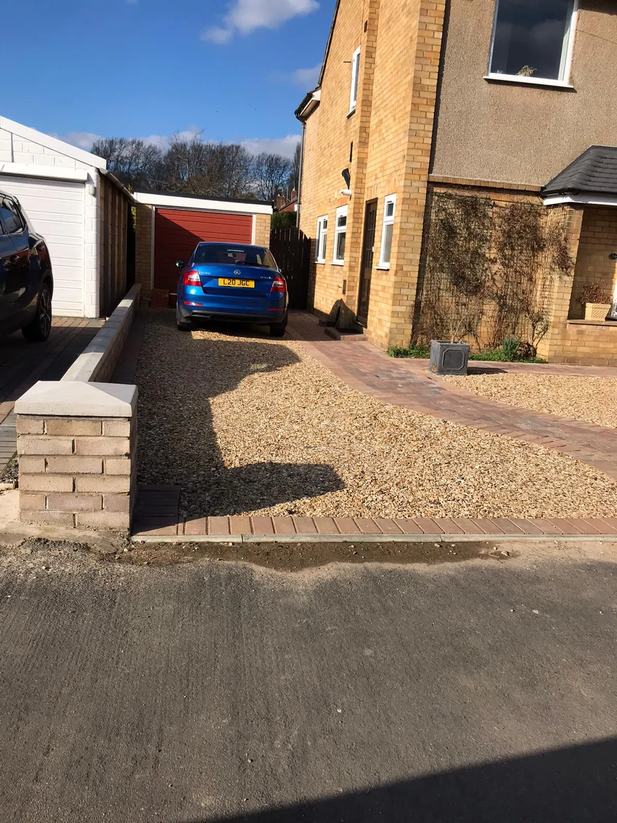Gravel driveway with block paving edging and a brick pier