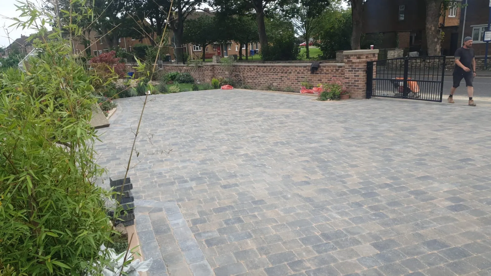 Grey cobble-effect block paving driveway with gates and bamboo