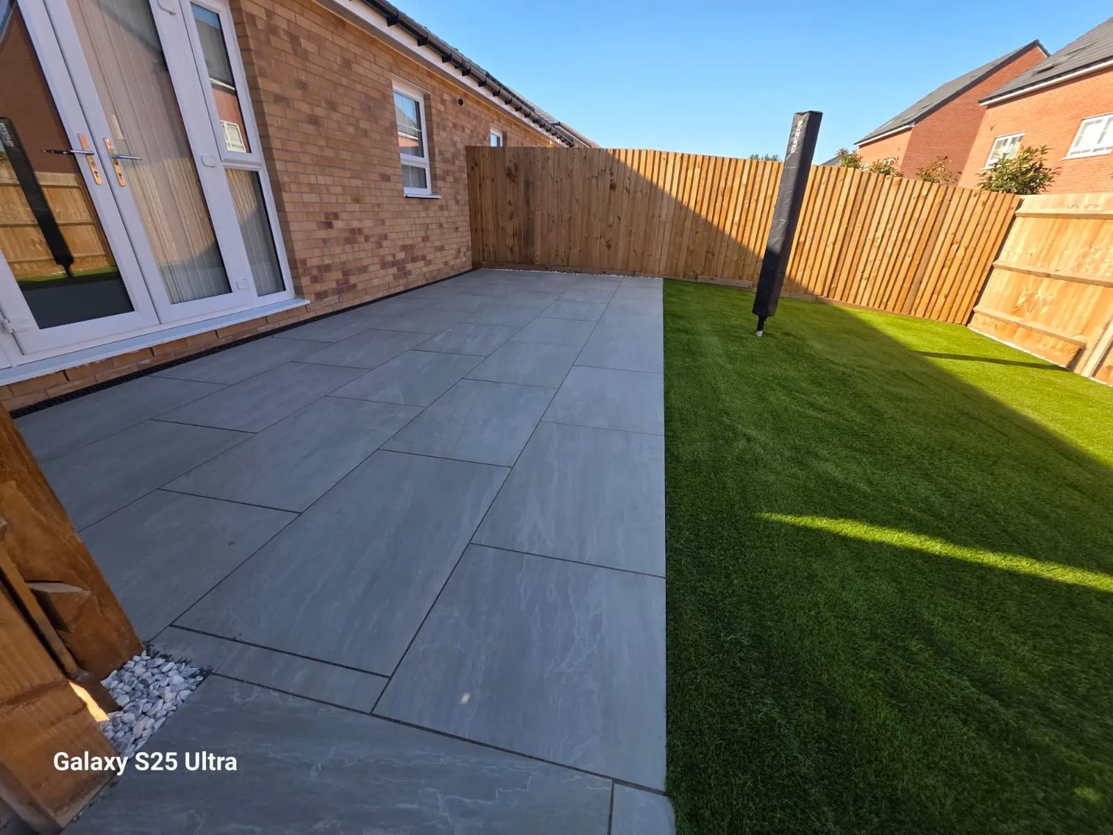 Grey porcelain patio beside artificial grass outside patio doors