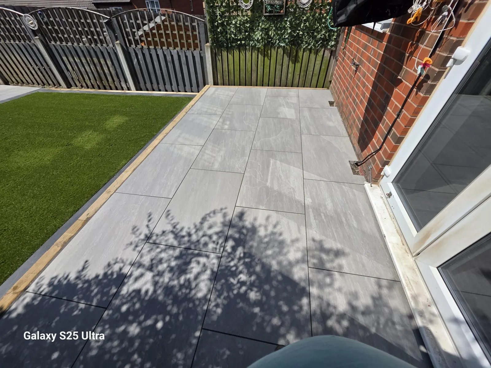 Grey porcelain patio and artificial grass along a side return