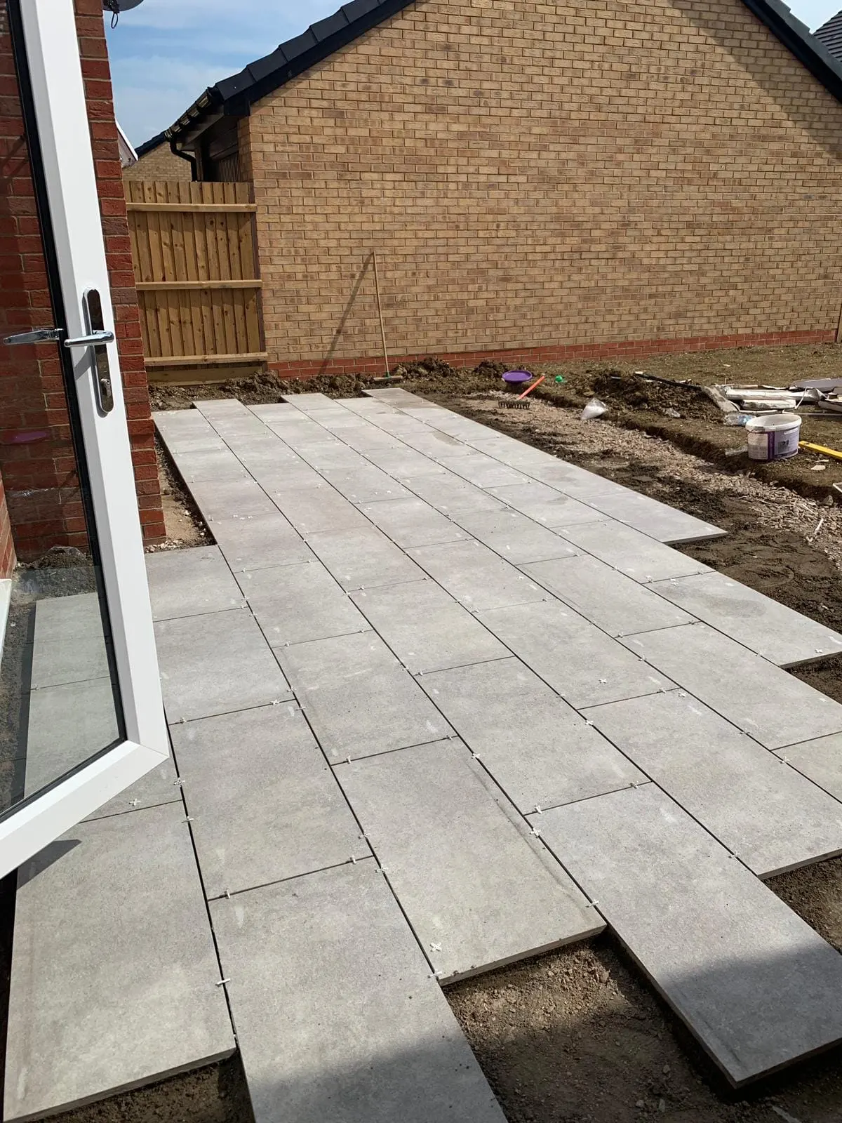 Grey porcelain slabs being laid outside patio doors