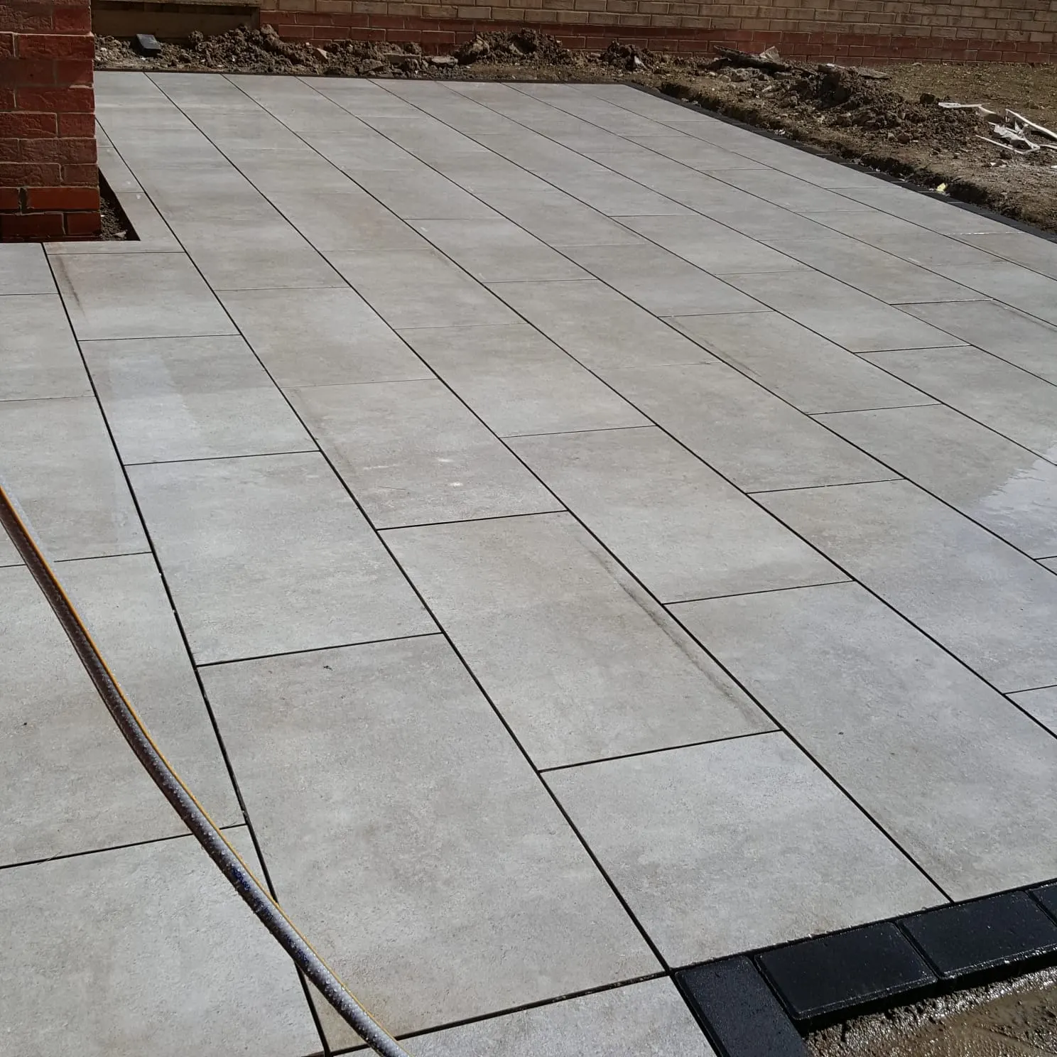 Grey porcelain patio with a charcoal block edge