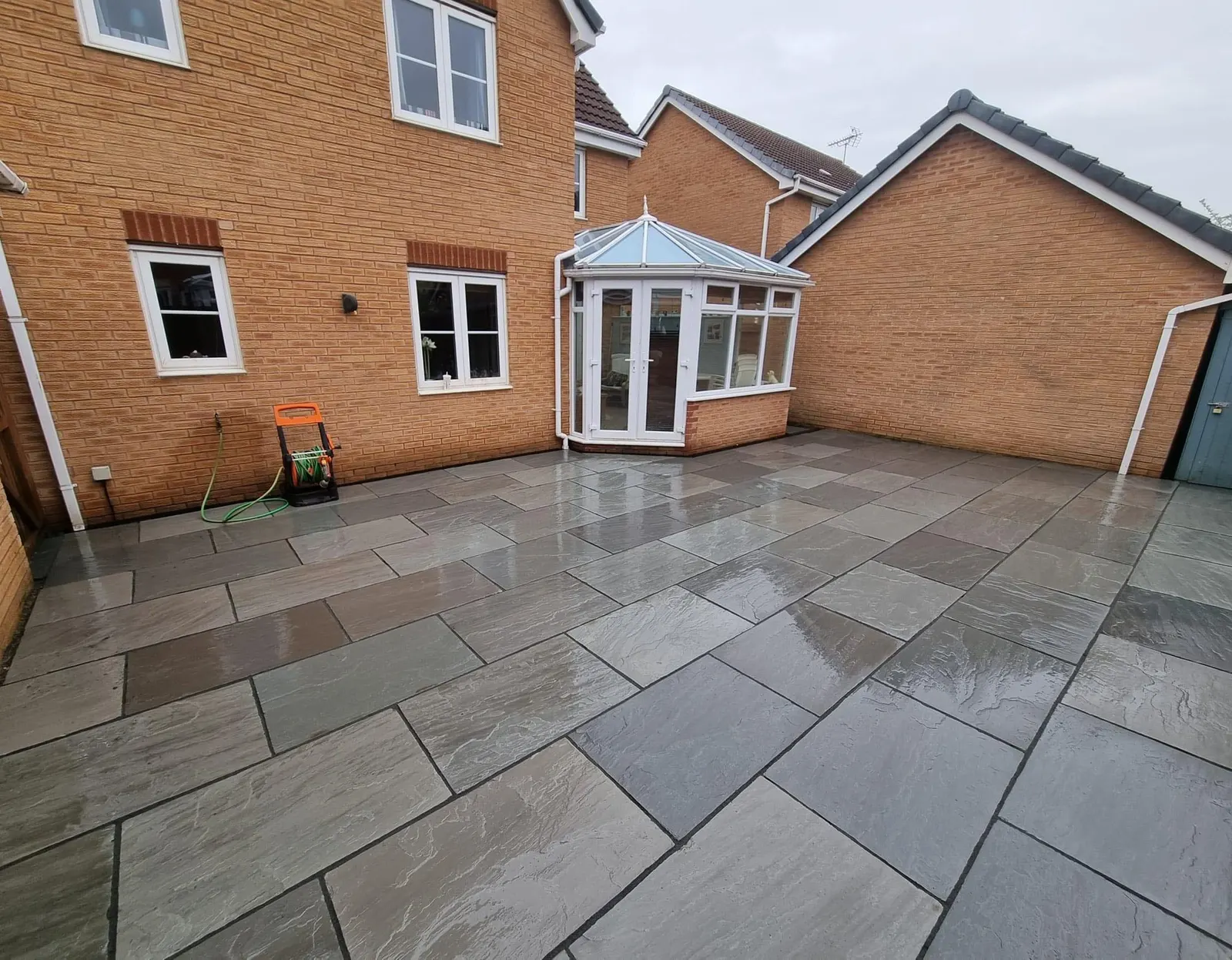 L-shaped grey porcelain patio round a house and conservatory